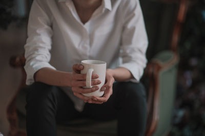 Midsection of woman holding coffee cup