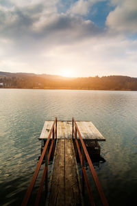 Pier over lake against sky during sunset