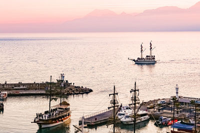 Sailboats sailing on sea against sky during sunset