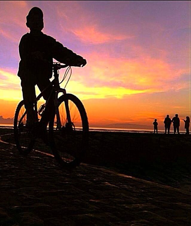 sunset, silhouette, orange color, sky, sea, men, bicycle, beach, leisure activity, lifestyles, horizon over water, scenics, beauty in nature, outline, cloud - sky, water, tranquil scene, dramatic sky