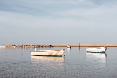 Sailboats moored in sea against sky