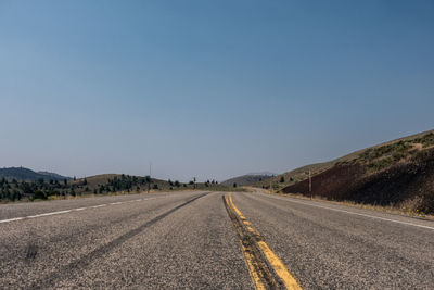 Empty road along landscape against clear sky