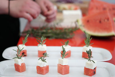 Close-up of watermelon and feta cheese cubes with rosemary on cutting board