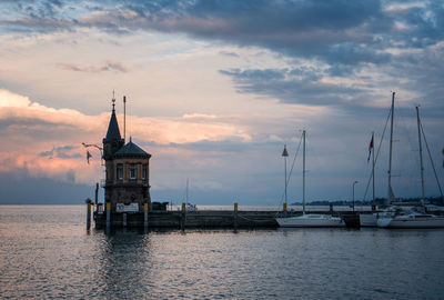 Sailboats in sea against sky during sunset