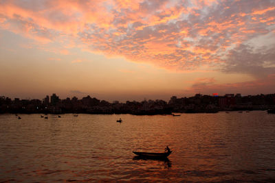 Silhouette boat in river against sky during sunset