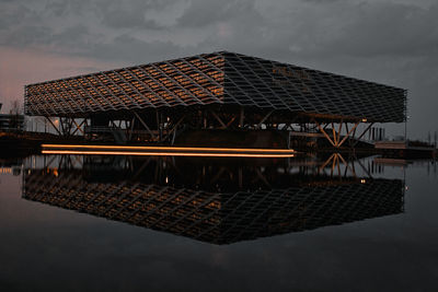 House by lake against sky at dusk