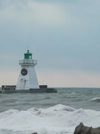 Lighthouse by sea against sky