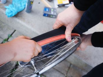 High angle view of hands repairing bicycle wheel