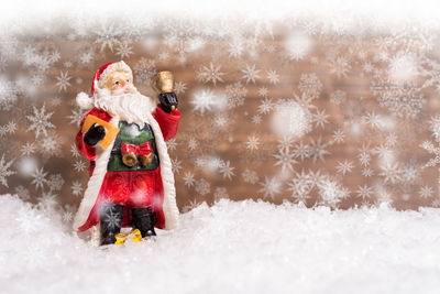 Digital composite image of santa claus figurine with snowflakes