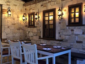 Chairs and table against illuminated wall in building