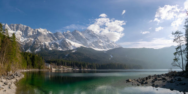 Scenic view of lake by snowcapped mountains against sky