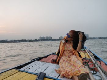 Woman on boat in sea against sky in city