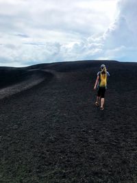 Rear view of woman walking on landscape against sky