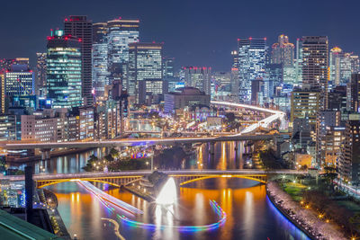 Illuminated bridge over river amidst buildings in city at night
