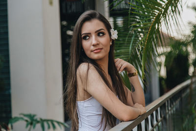 Portrait of beautiful young woman standing by railing
