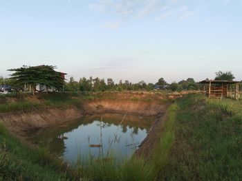 Scenic view of lake and trees on field against sky