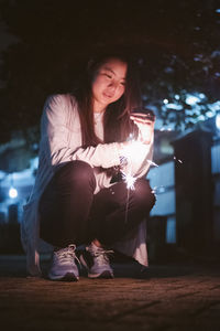 Young woman sitting in illuminated city at night