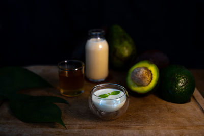 Close-up of healthy drink with bottle of milk, honey, avocado and ingredients on table.