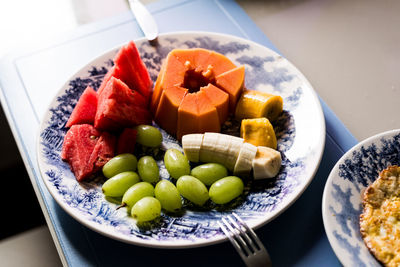 Morning food with fried egg papaya watermelon grape and bananas inside a plate. healthy eating. 