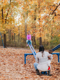 Mother and kids playing in park during autumn