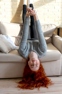 Smiling girl exercising on sofa at home