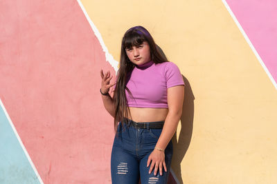 Portrait of fancy teen woman posing against colorful wall