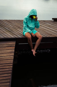 Man sitting on wood against sky