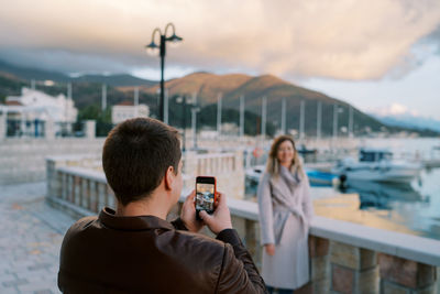 Side view of woman photographing against sky