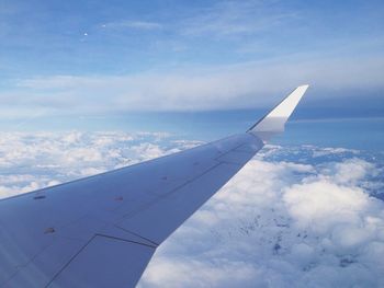 Cropped image of airplane flying over clouds