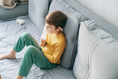  boy sits with an inhalation mask during cough and bronchitis. treatment with an inhaler at home