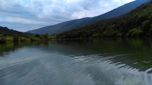 Scenic view of lake by mountains against sky