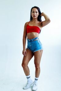 Portrait of young woman standing against white background