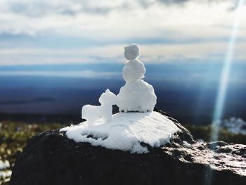 Close-up of snow on rock against sky