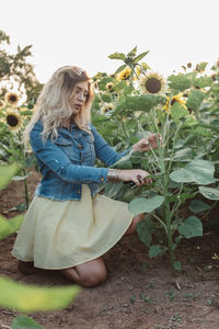 Woman standing by sunflower against plants