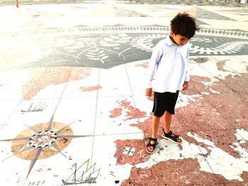Full length of boy standing on map patterned floor at playground