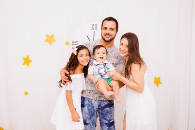 Portrait of cheerful family standing against wall