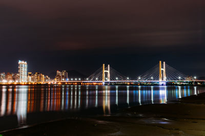 Illuminated bridge over river at night