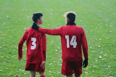 Rear view of siblings standing on field