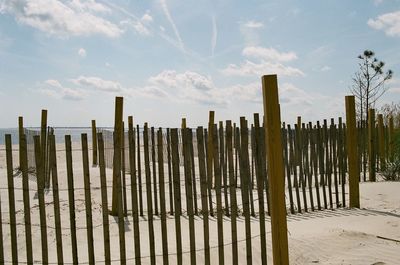 Wooden fence on beach against sky
