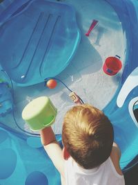 Rear view of playful boy with toys in wading pool