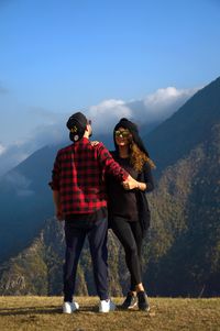 Full length of couple standing on mountain against sky