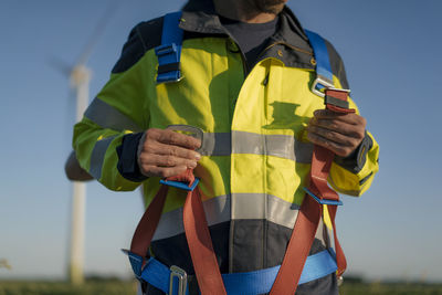 Close-up of technician at a wind farm putting on climbing harness