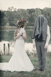 Bride covering face with bouquet and groom with coat while standing on field