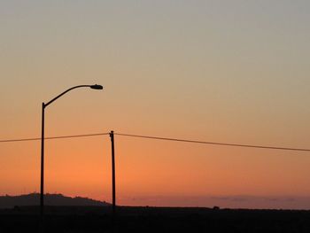 Silhouette power lines against sky during sunset