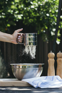 A woman's hand sifting flour for baking