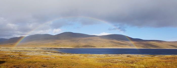 Scenic view of rainbow over mountains against sky