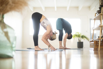 A couple in forward fold position during yoga.