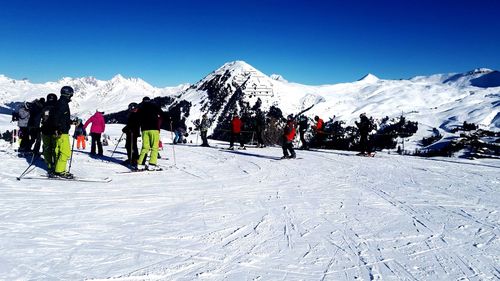 Group of people on snowcapped mountain against sky