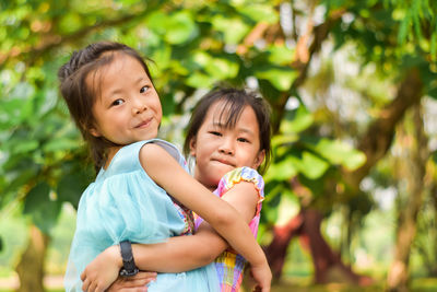 Asian sister carrying her little girl in a summer green park.