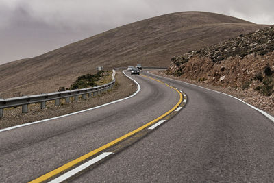 Road leading towards mountains against sky